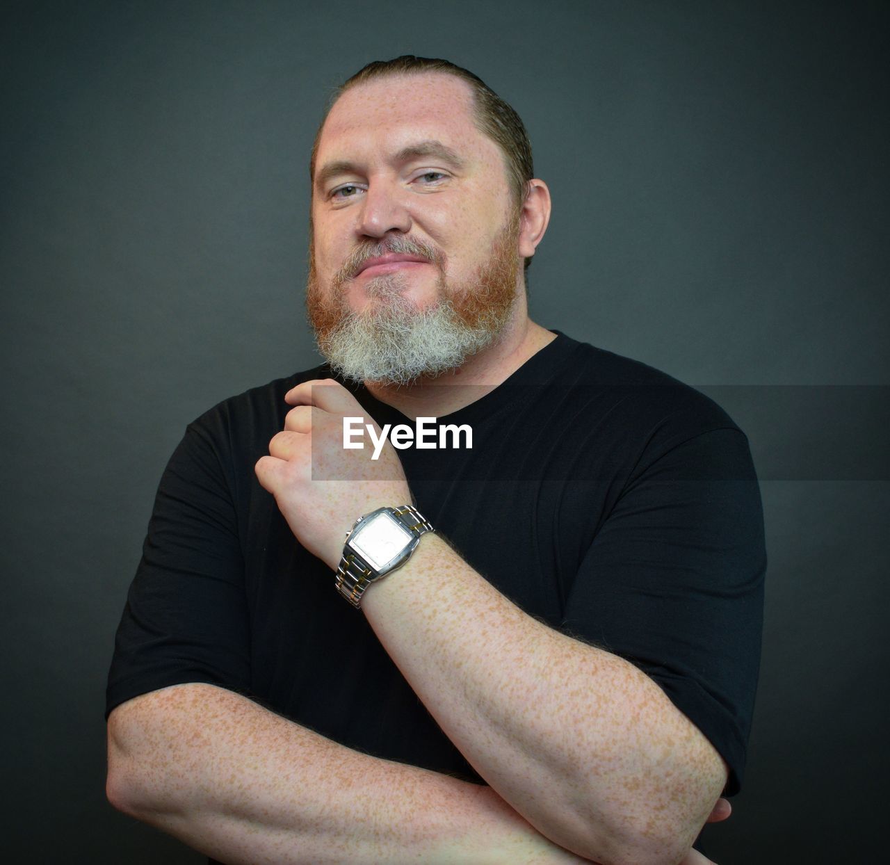 one person, adult, watch, studio shot, portrait, men, facial hair, beard, mature adult, indoors, gray, looking at camera, wristwatch, arm, arms crossed, gray background, person, waist up, tattoo, black background, casual clothing, front view, time, emotion, lifestyles, finger, individuality, hand, looking, serious, cut out, copy space, black, shaved head, colored background, human hair, t-shirt