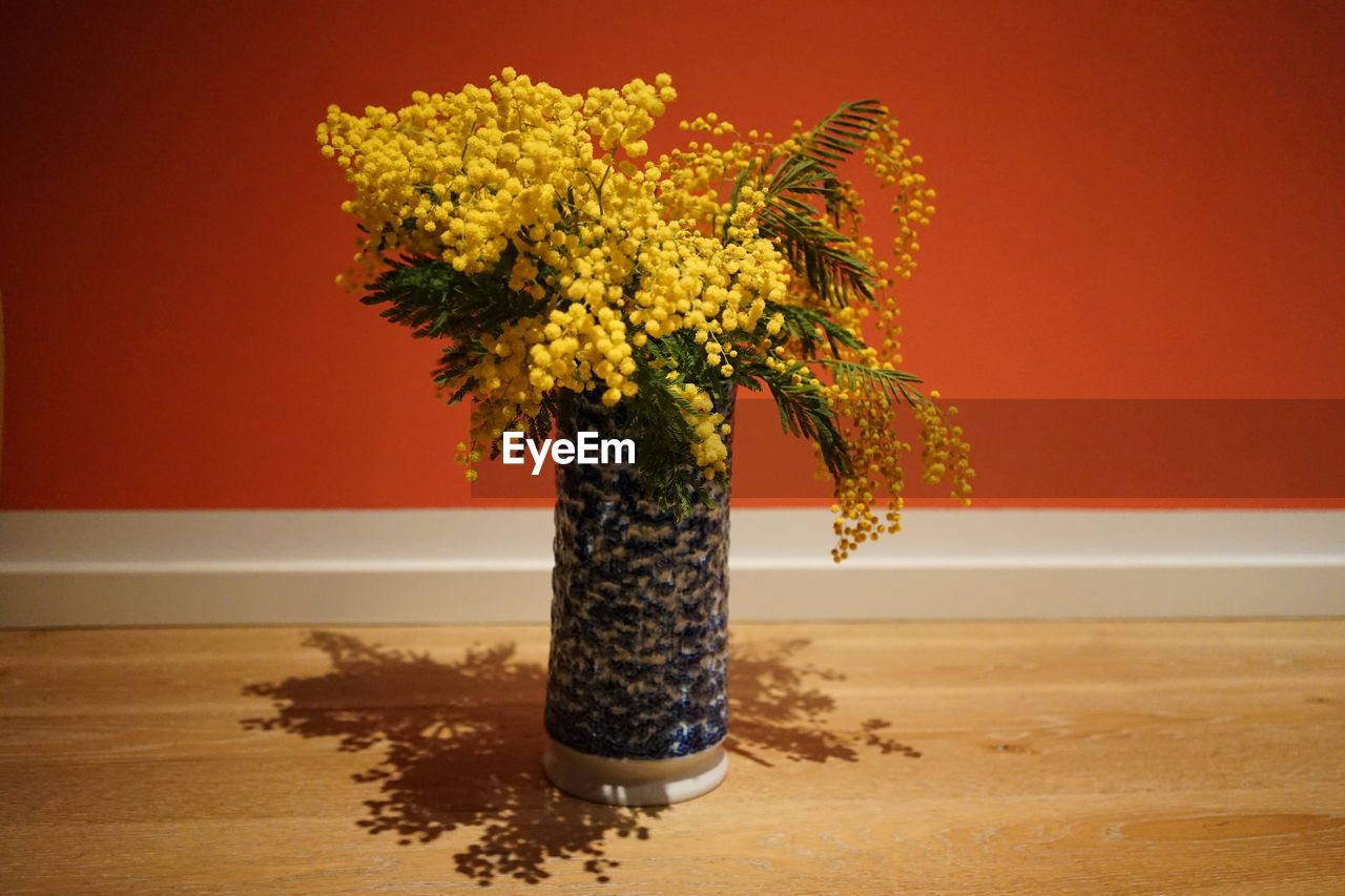 Close-up of vase on table against orange wall