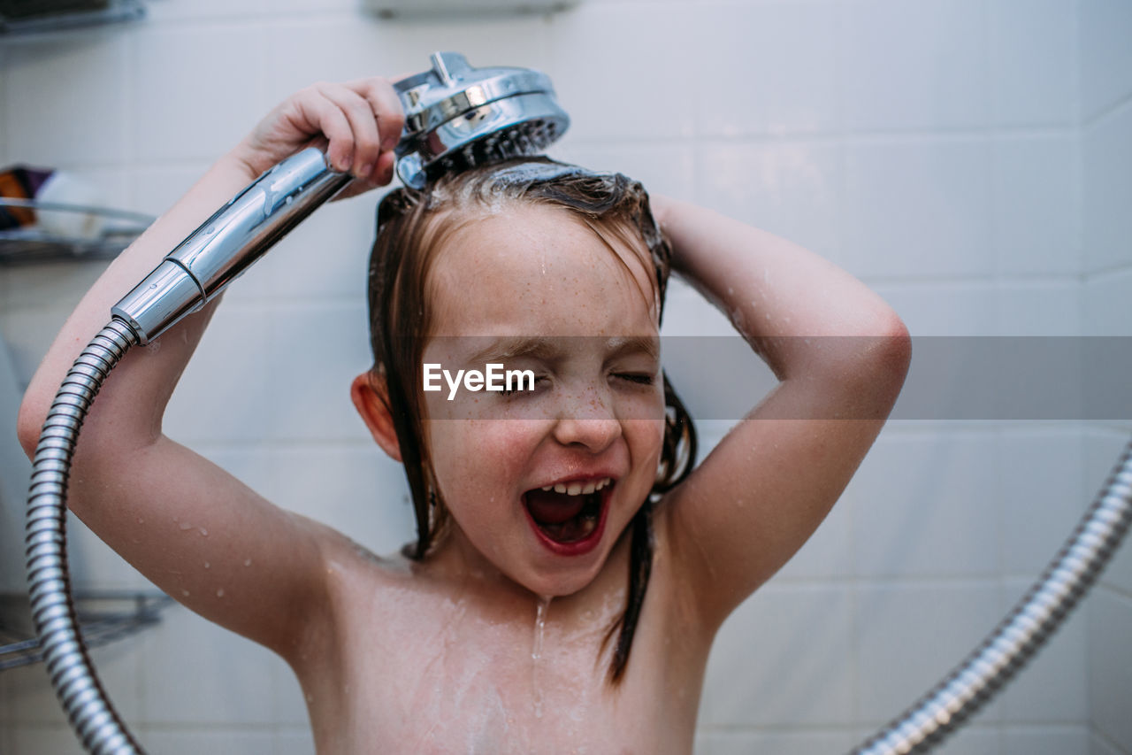 Close up of young girl rinsing shampoo from hair in shower