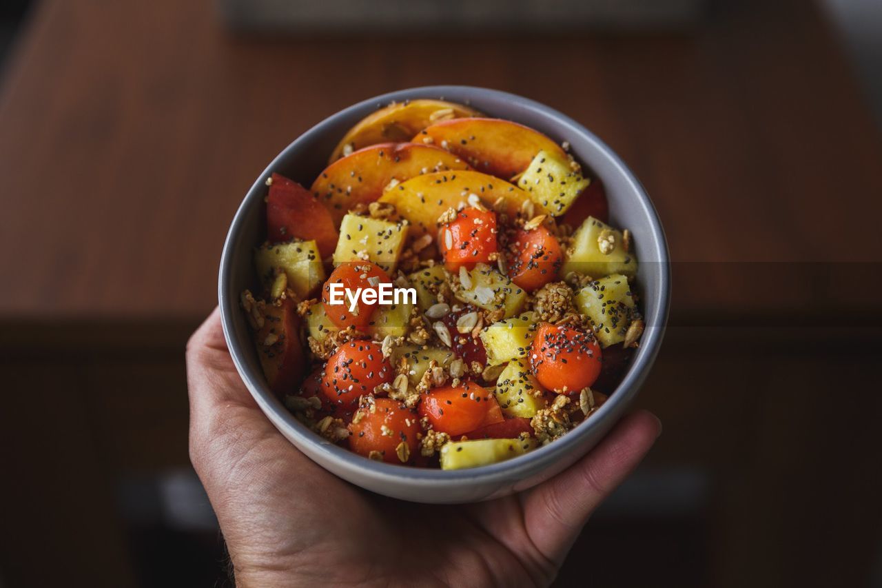 High angle view of hand holding salad in bowl on table