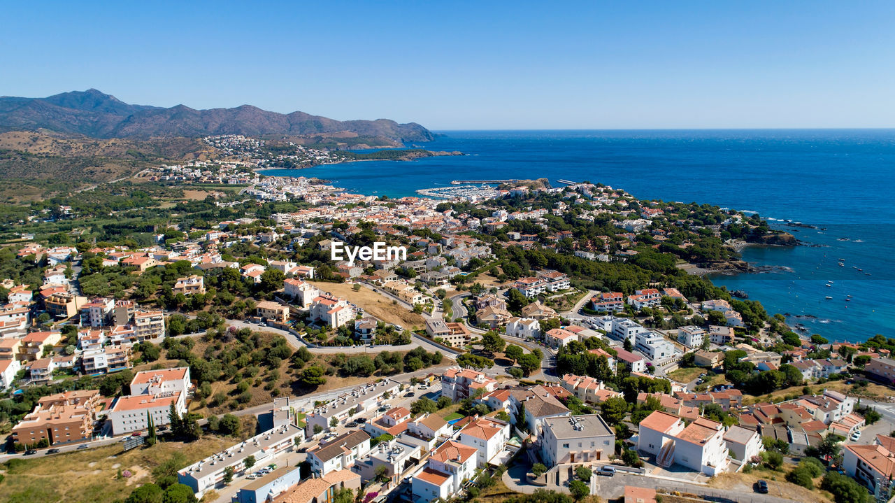 High angle view of townscape by sea against clear sky