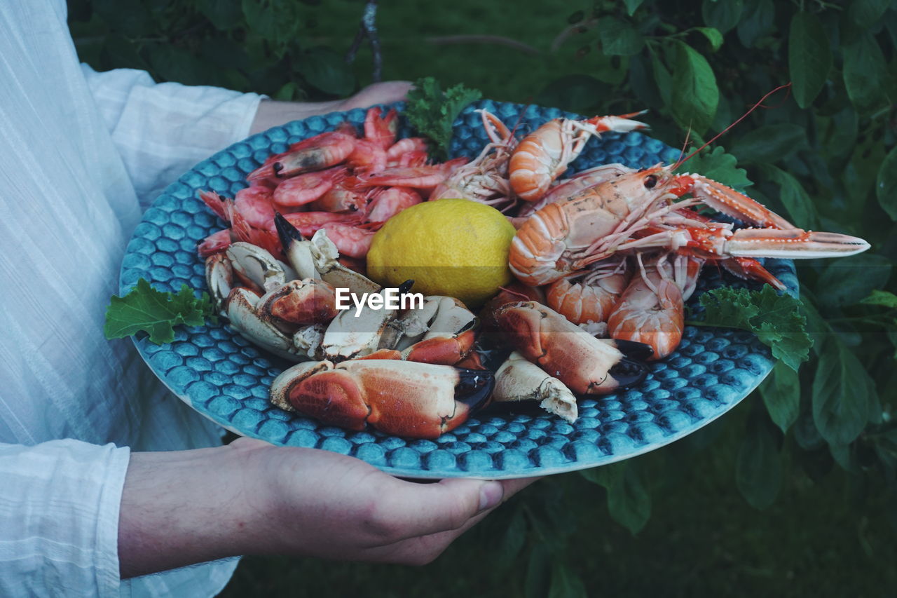 Midsection of woman holding seafood in plate