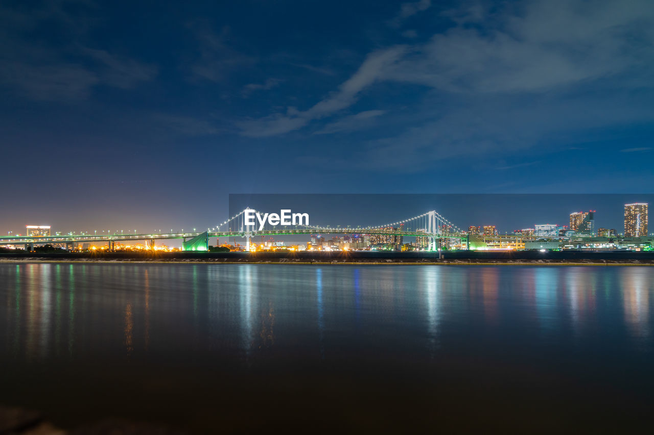 ILLUMINATED BRIDGE OVER RIVER IN CITY