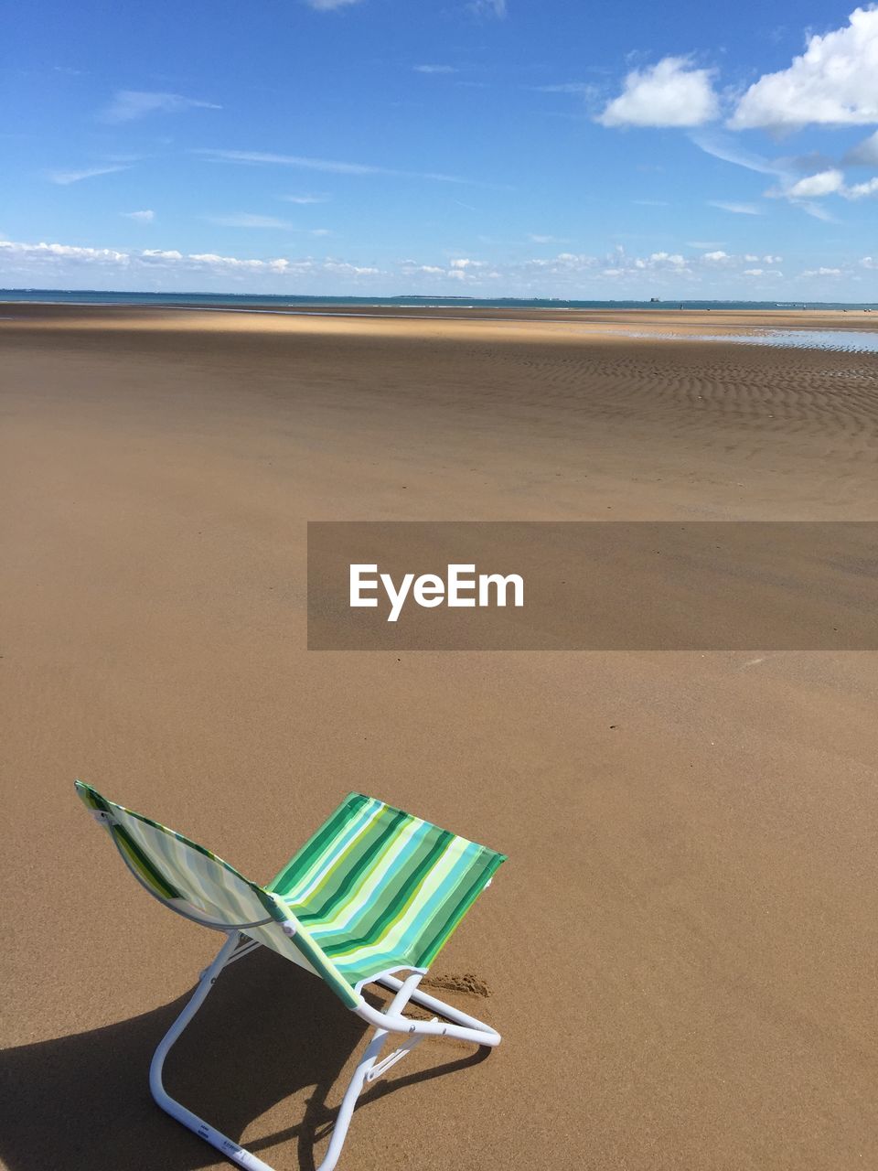 Deck chair at beach against sky