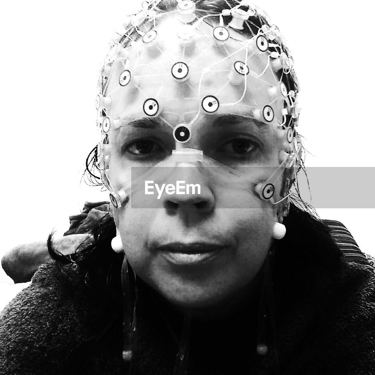 Close-up portrait of woman wearing eeg against wall at home