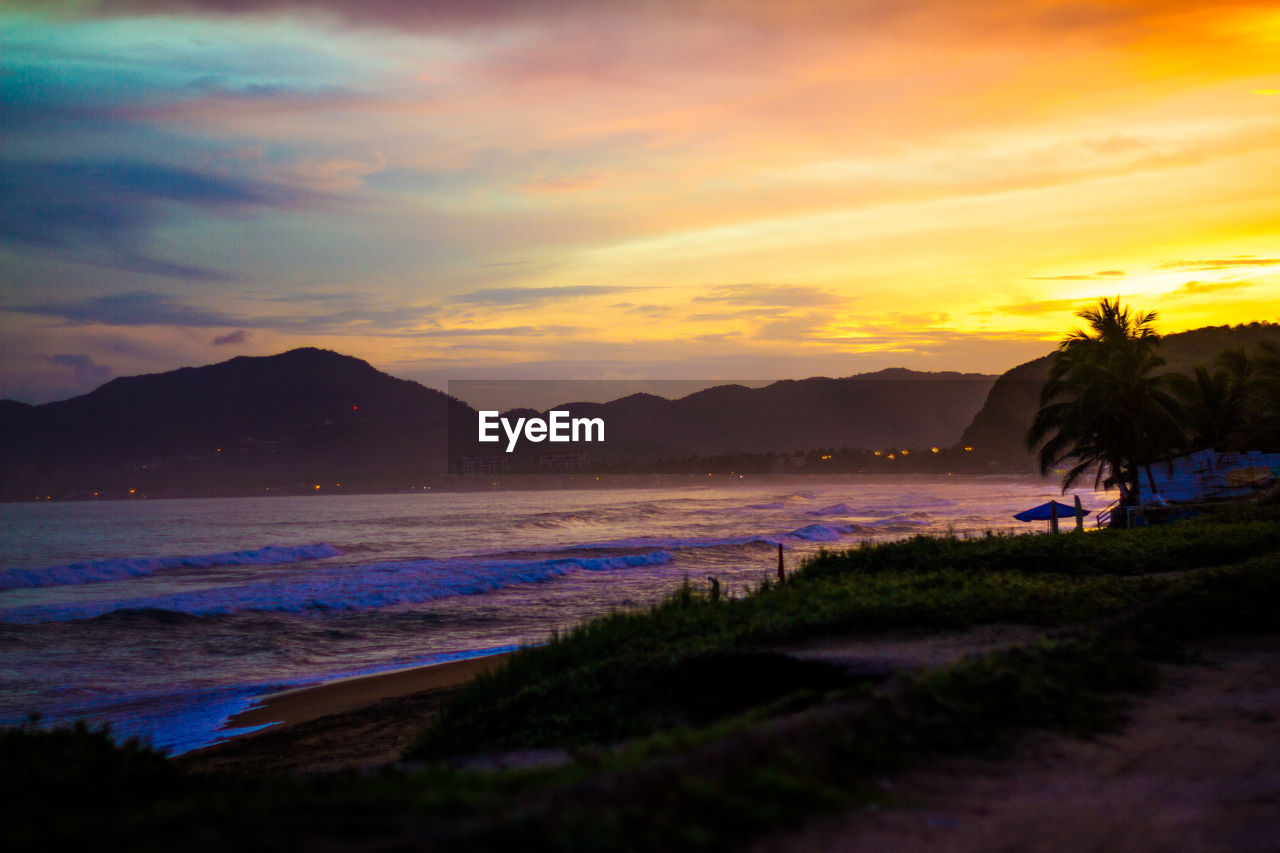 SCENIC VIEW OF BEACH AND SEA AGAINST SKY AT SUNSET