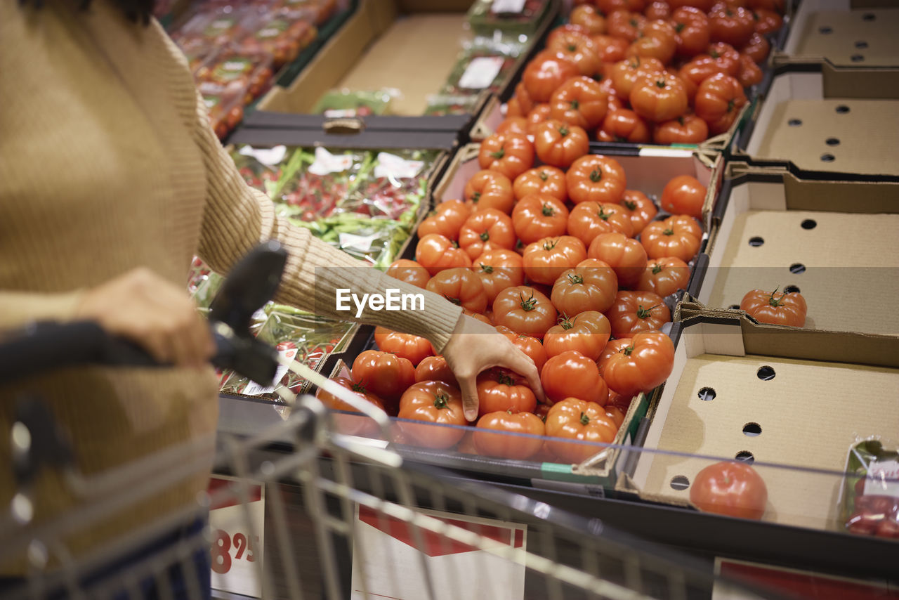 Woman's hand holding beefsteak tomato in supermarket