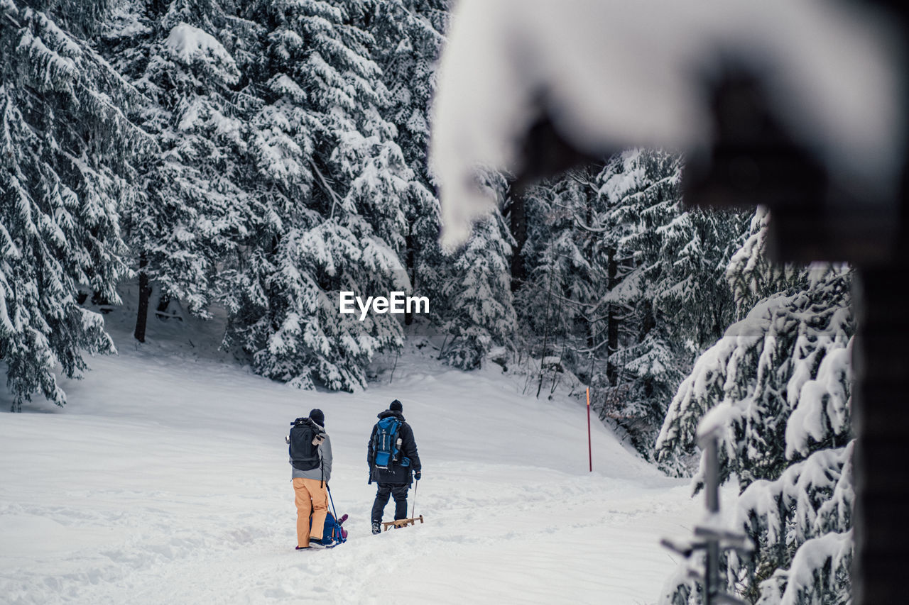 REAR VIEW OF PEOPLE WALKING ON SNOW COVERED STREET