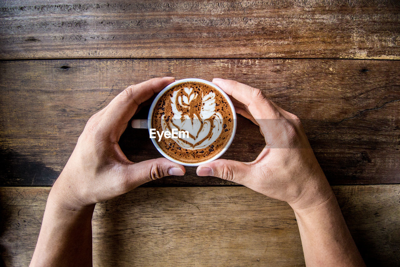 Cropped hands holding coffee on table