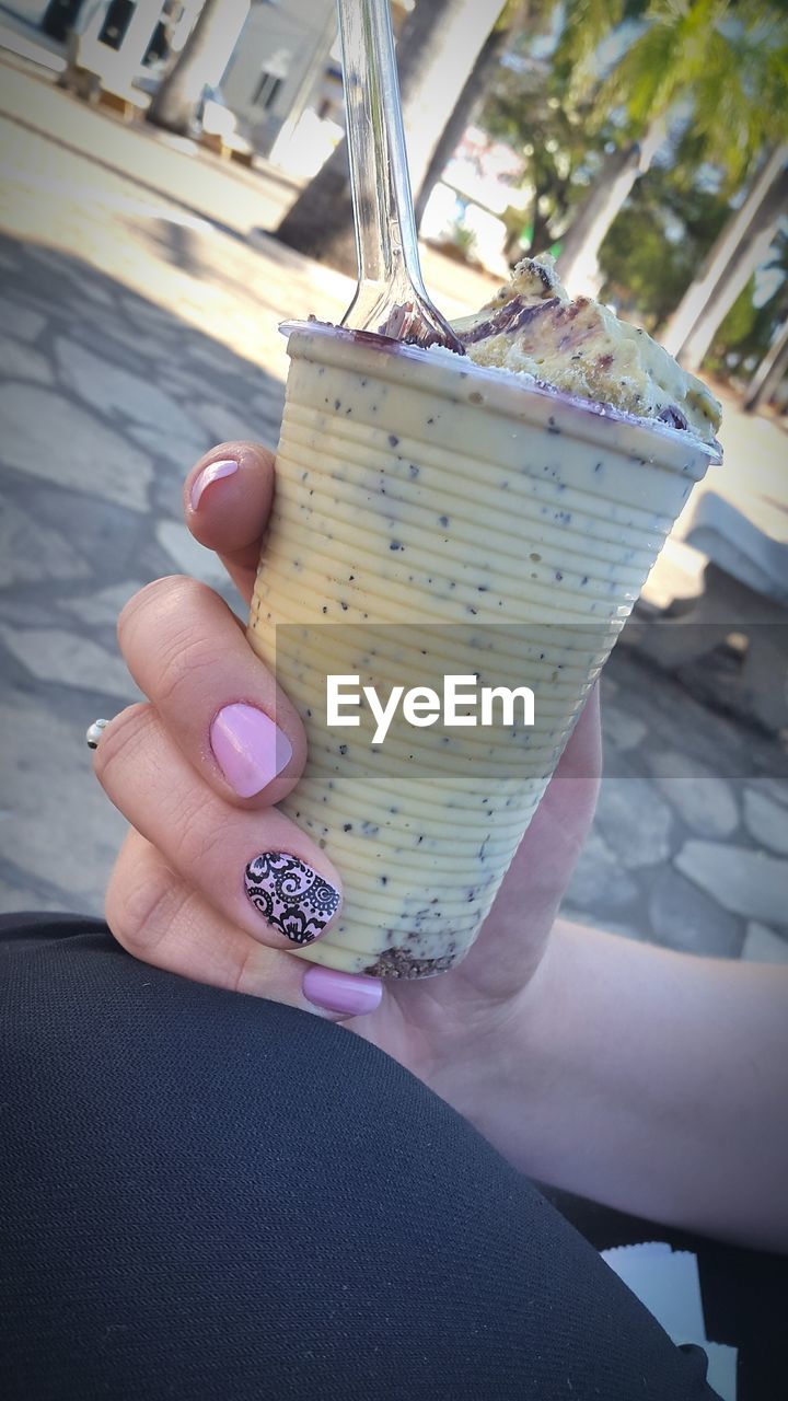 CLOSE-UP OF WOMAN HOLDING ICE CREAM CONE