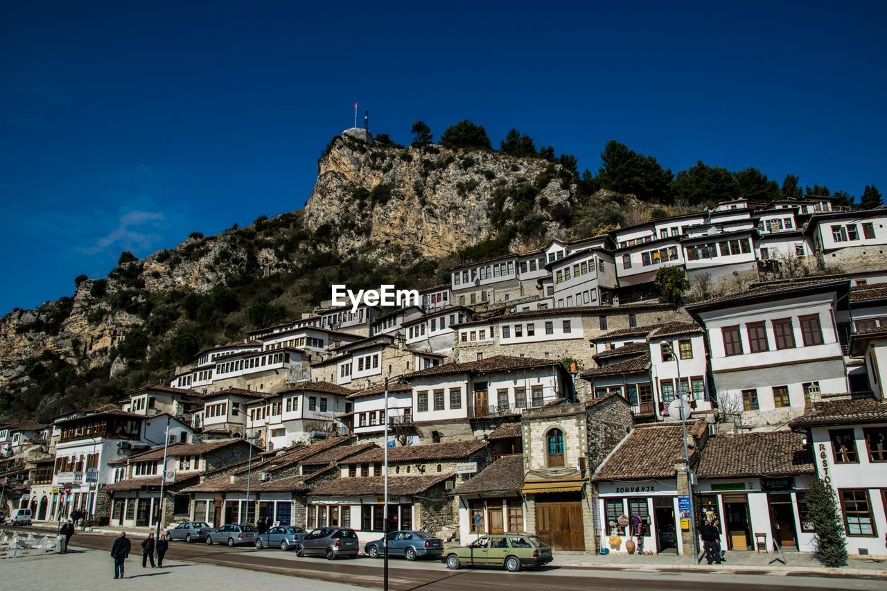 LOW ANGLE VIEW OF BUILDINGS AND MOUNTAINS AGAINST CLEAR BLUE SKY