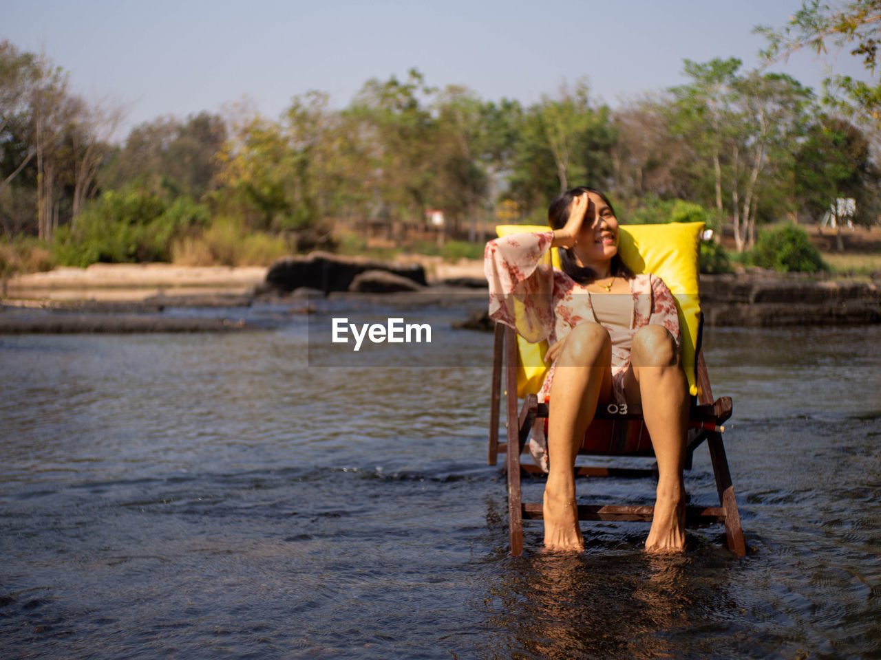 Full length of woman sitting on shore against sky