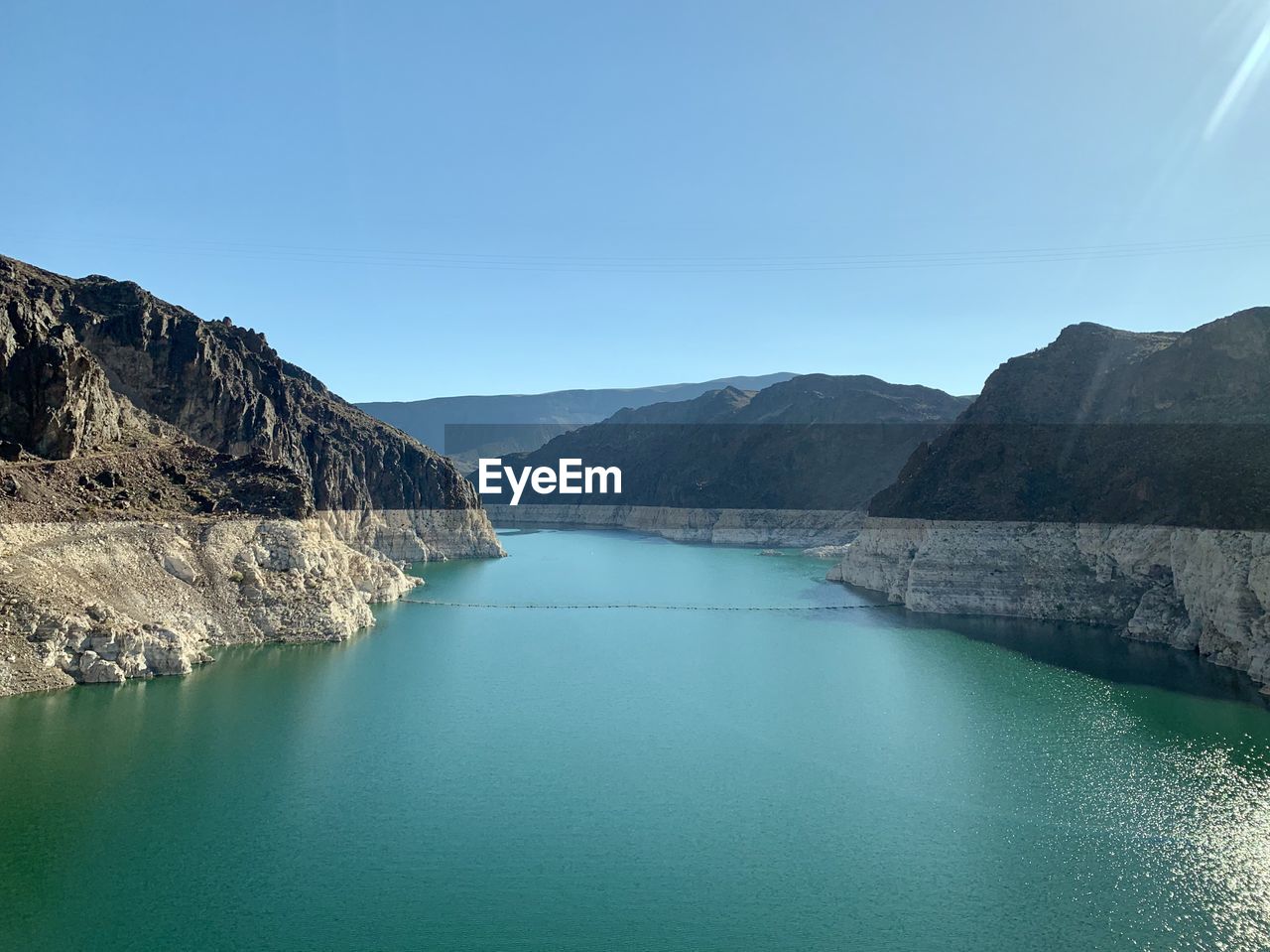 Scenic view of lake and mountains against clear blue sky