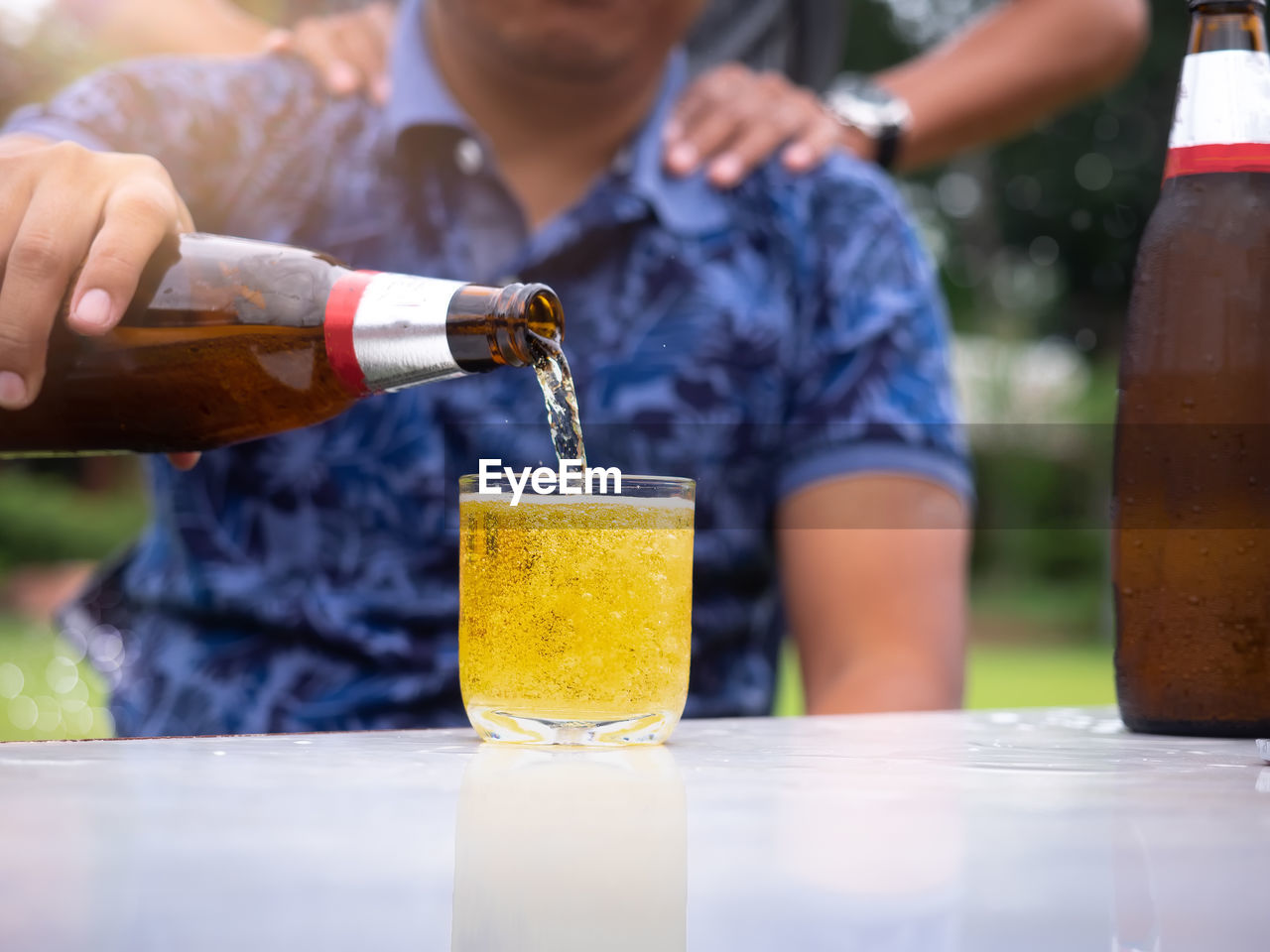 Beer bottle with a glass on a white table, friendship and celebration concept.