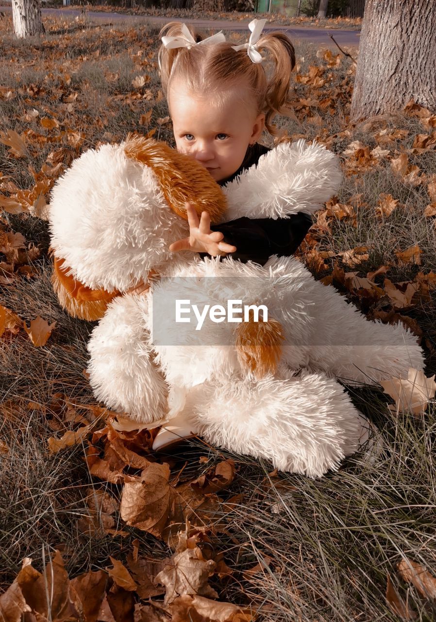 High angle view of cute girl with toy sitting on grass