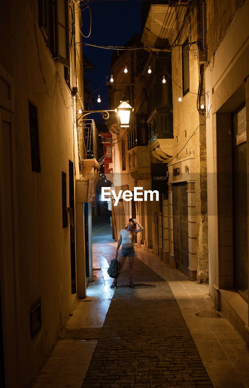 STREET AMIDST BUILDINGS AT NIGHT