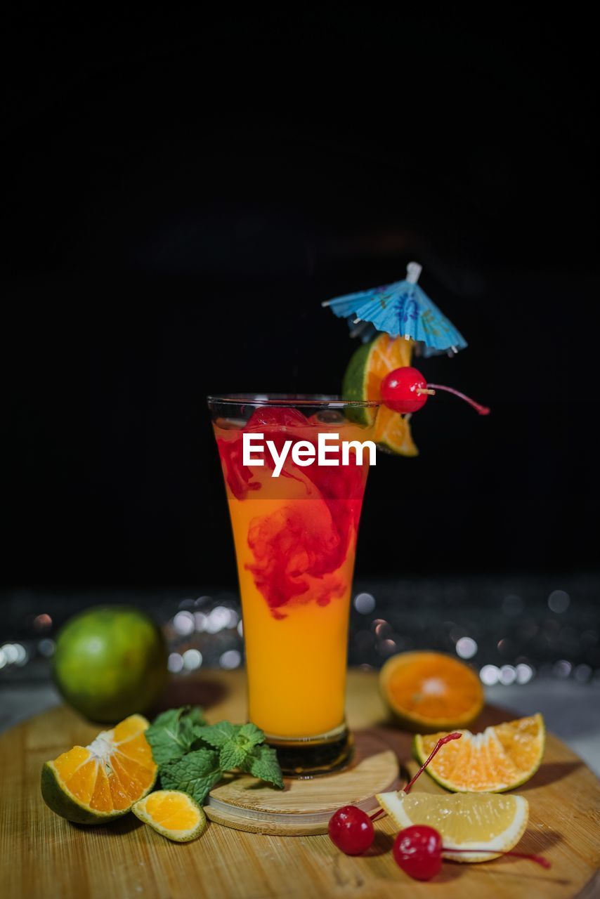 Close-up of drink with fruits on table against black background