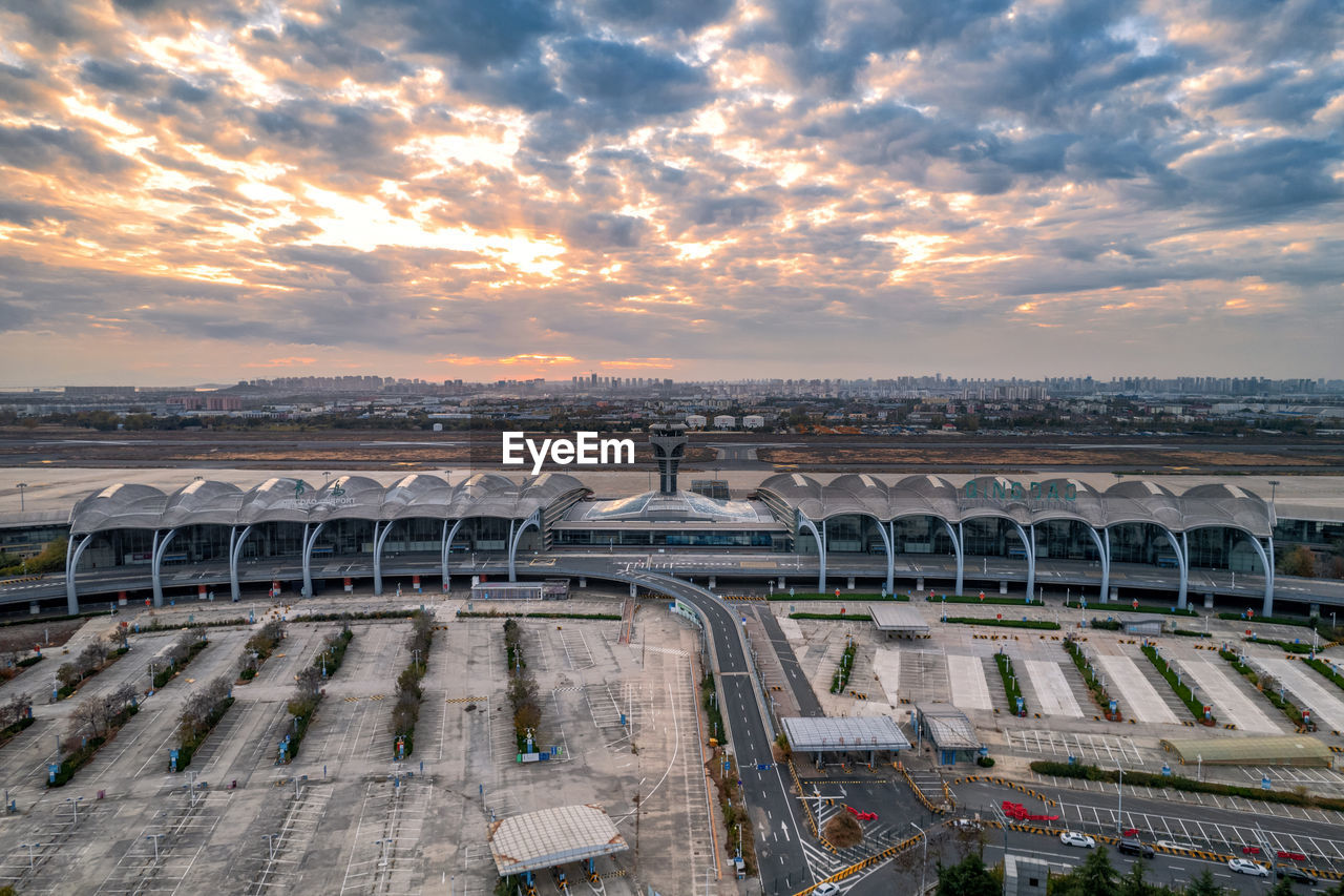 architecture, sky, sport venue, stadium, sunset, cloud, built structure, high angle view, nature, travel, arena, travel destinations, city, transportation, outdoors, building exterior, environment, tourism, sports, water, no people, cityscape, arts culture and entertainment, business finance and industry