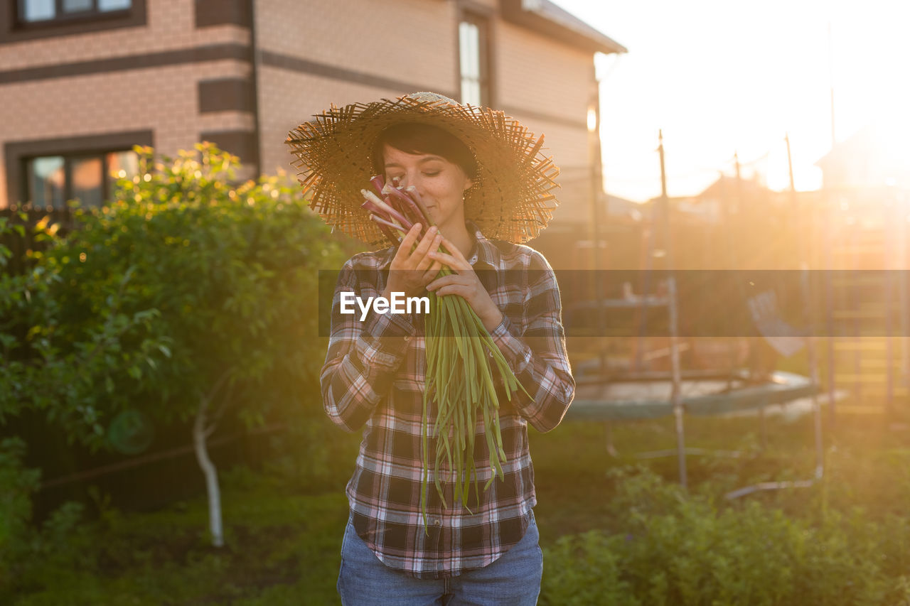 Woman smelling vegetable while standing outdoors