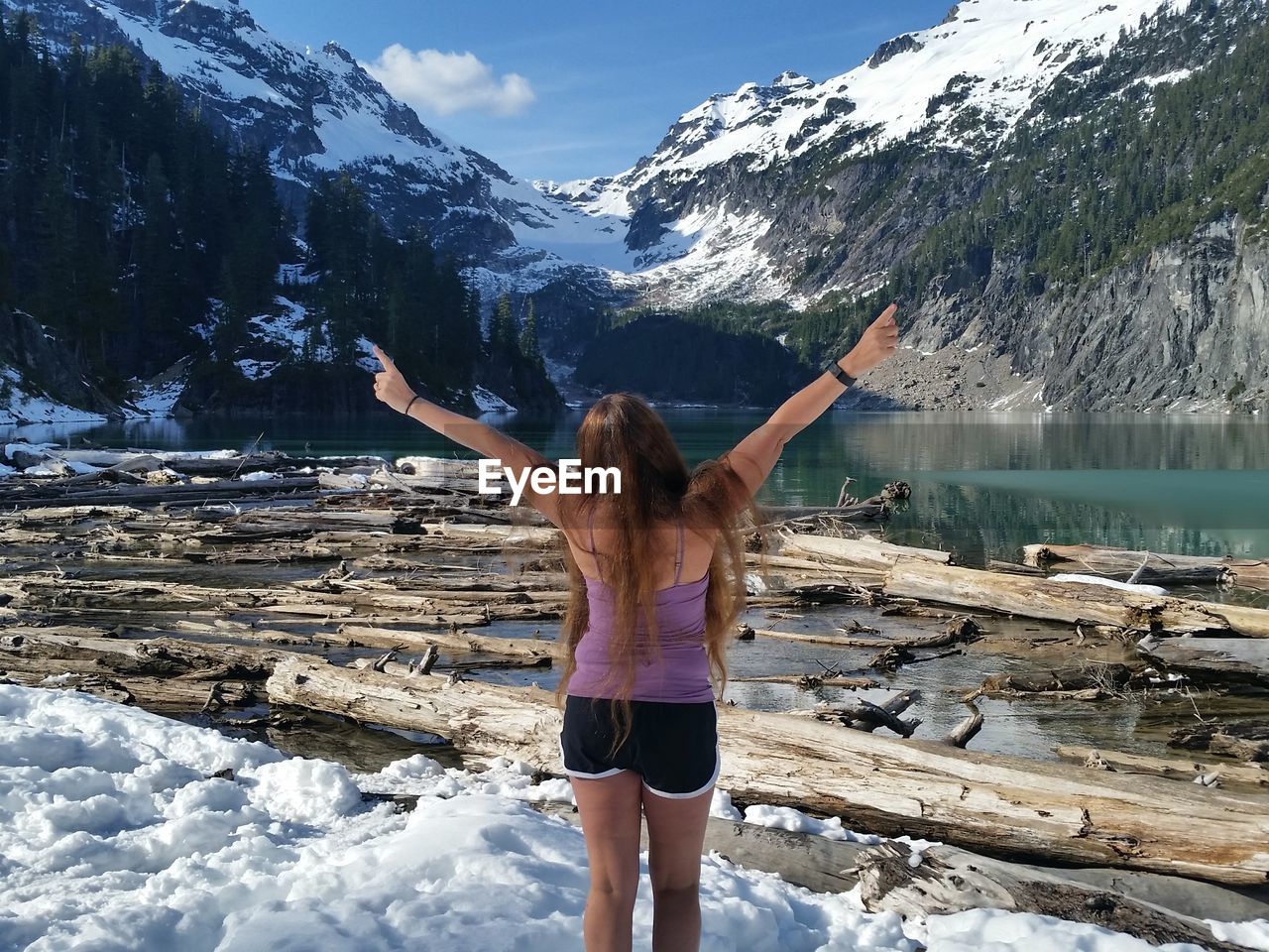 Rear view of woman standing against lake and mountain during winter