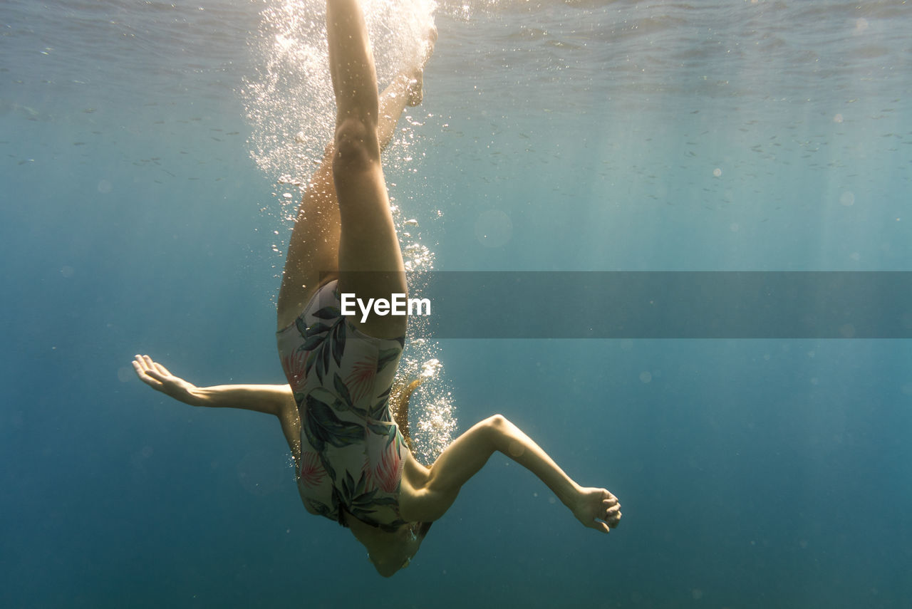 Woman swimming upside down in sea
