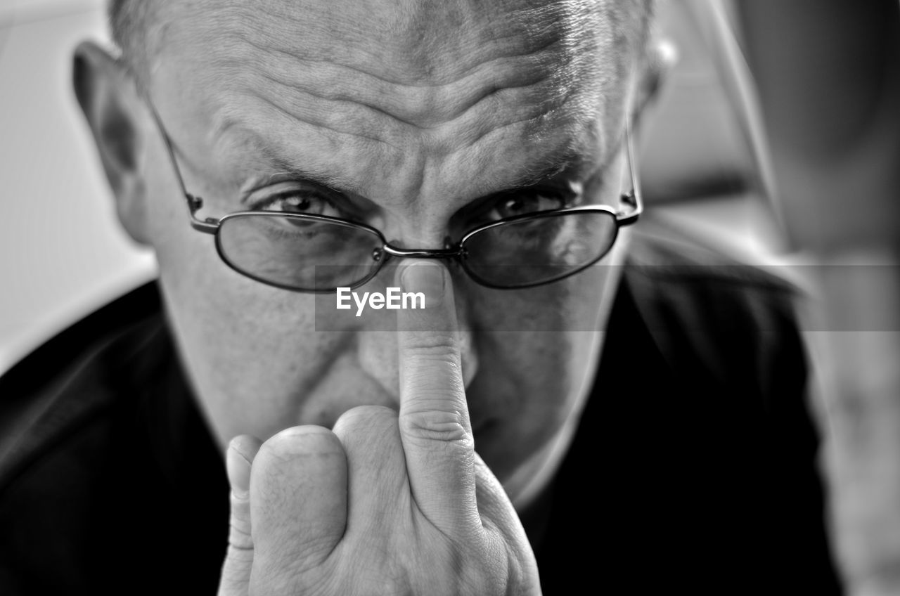 Close-up portrait of angry man adjusting eyeglasses