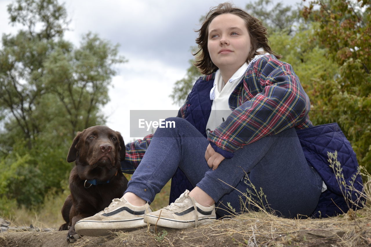 FULL LENGTH OF MAN SITTING WITH DOG