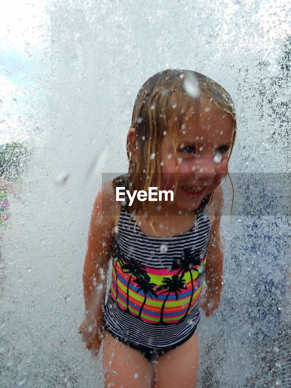 Cute little girl enjoying fountain during summer
