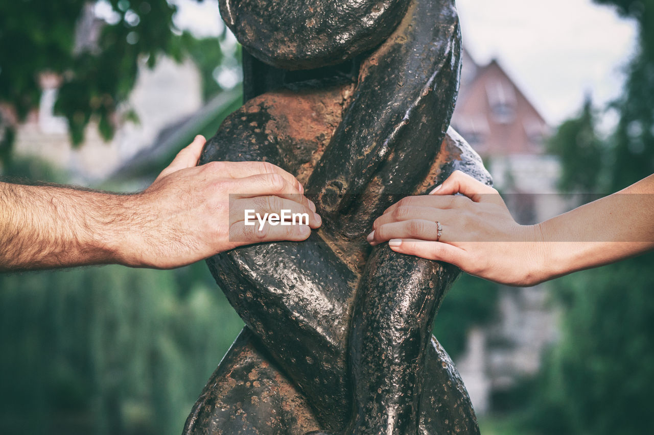 Cropped hands of people touching structure at public park