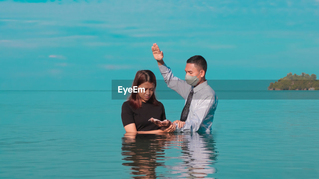 Portrait of a woman being baptized by a priest from the adventist church