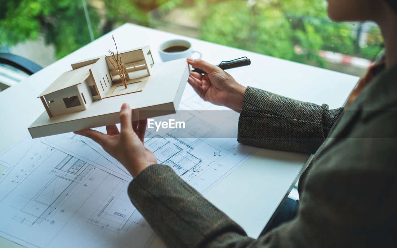 Midsection of architect holding model house