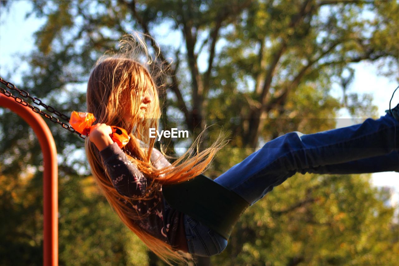 Side view of girl swinging at playground