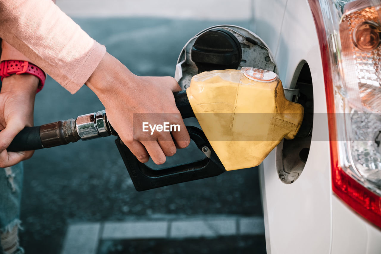 Woman hands pumping gasoline fuel in car at gas station.