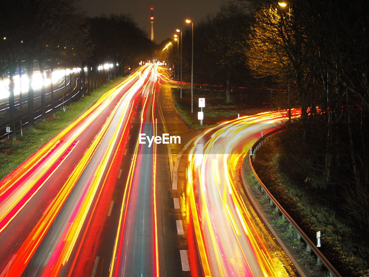 light trail, illuminated, night, long exposure, motion, speed, transportation, road, traffic, city, street, tail light, blurred motion, architecture, light, highway, street light, no people, mode of transportation, city life, motor vehicle, lighting equipment, multi colored, car, city street, infrastructure, nature, built structure, light - natural phenomenon, outdoors, headlight, building exterior, the way forward, red, sky, high angle view, lane, evening, travel destinations, on the move, travel, glowing, plant, tree, darkness, multiple lane highway