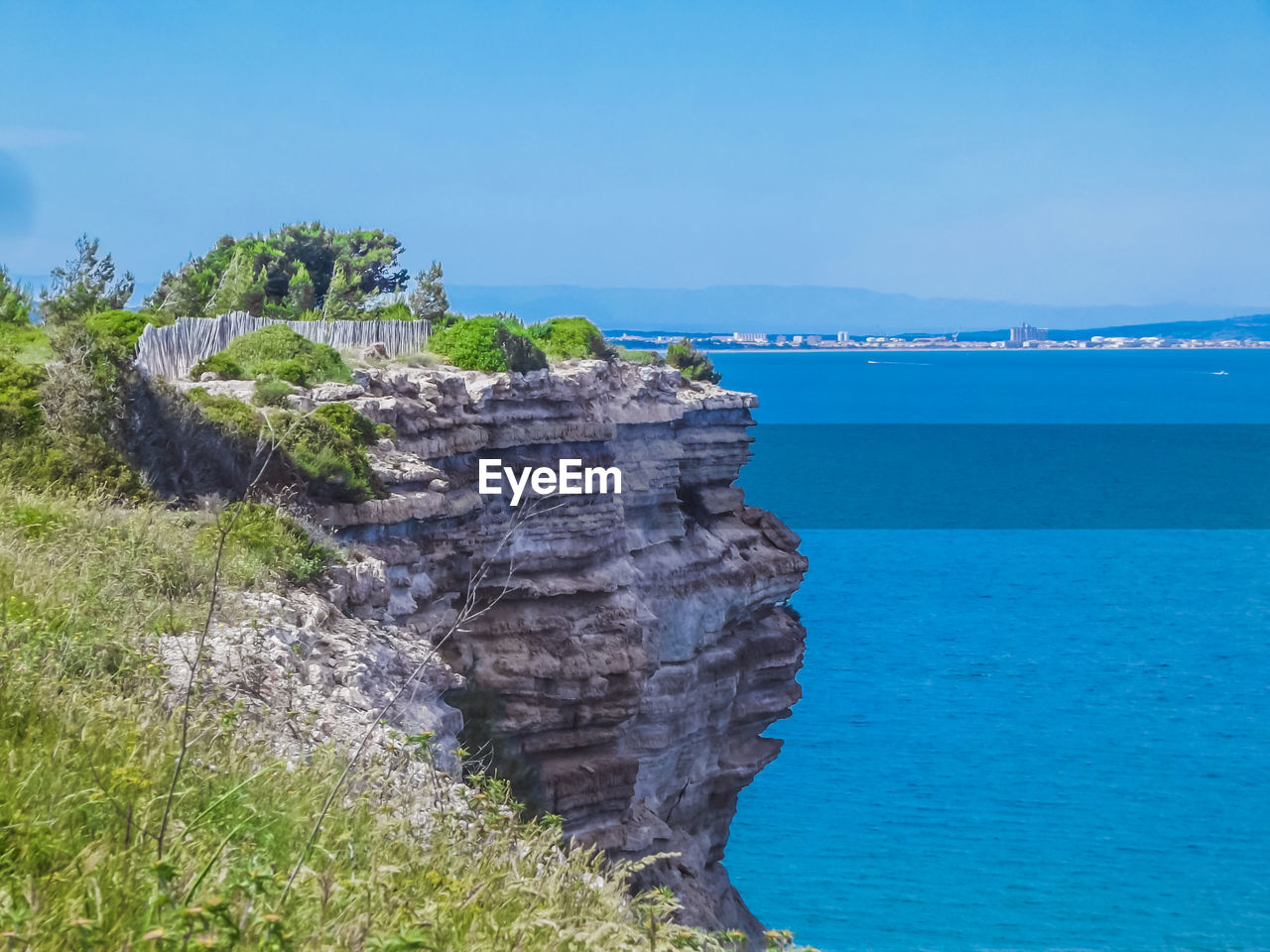 Rock formations by sea against blue sky