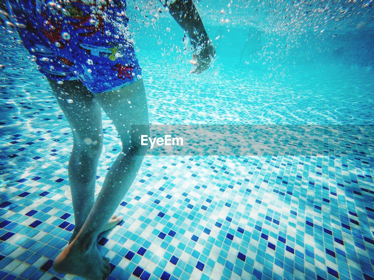 Low section of person swimming in pool