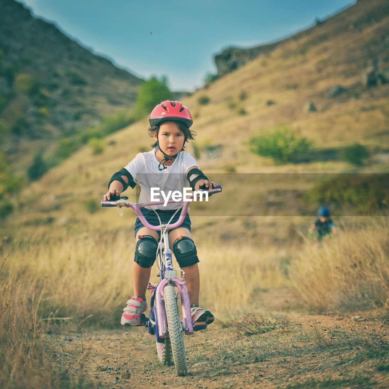 FULL LENGTH OF BOY RIDING BICYCLE ON FIELD