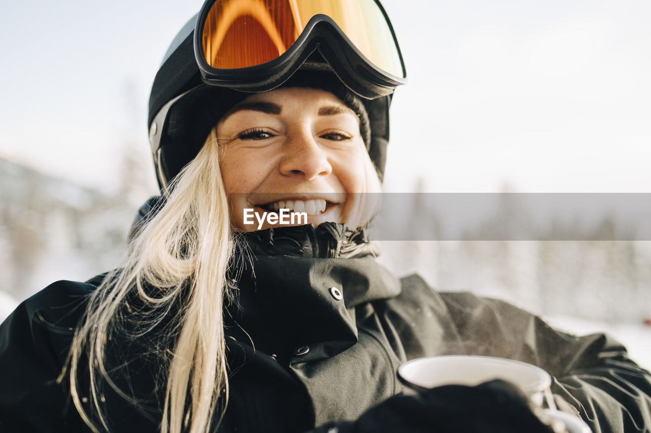 Portrait of smiling blond woman wearing ski goggles and helmet