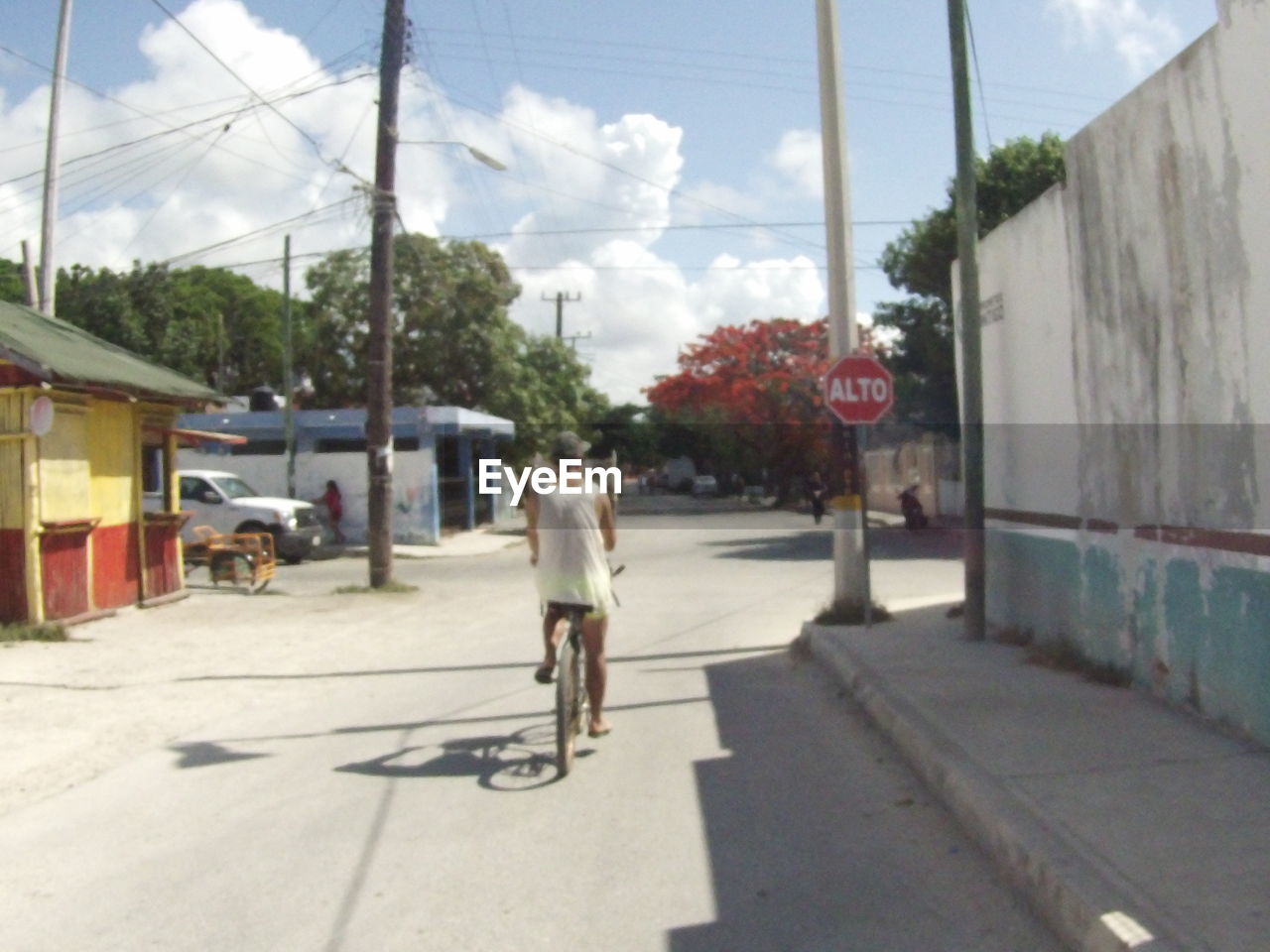 REAR VIEW OF WOMAN RIDING BICYCLE ON STREET