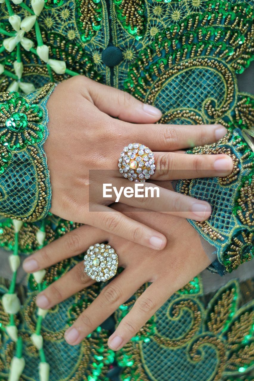 Midsection of woman in green dress wearing rings