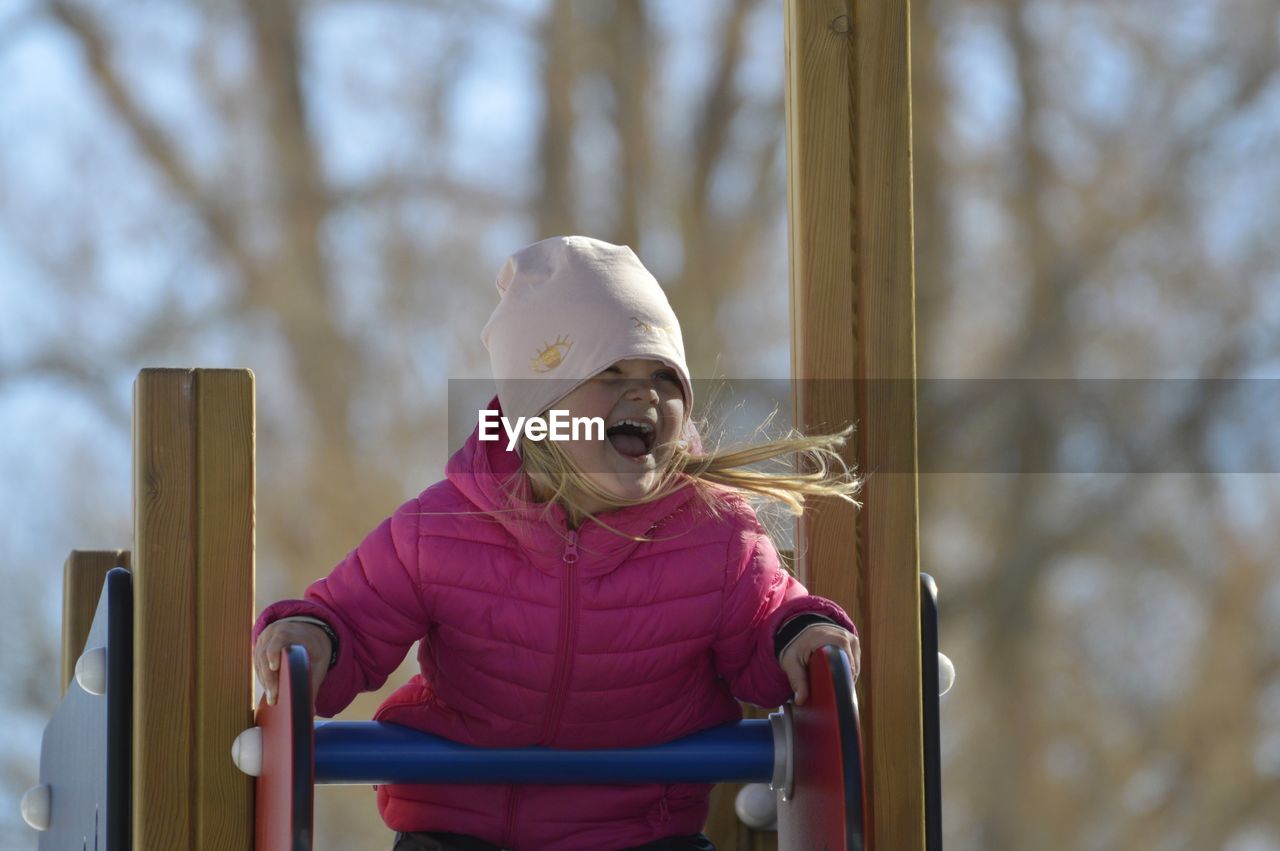 Low angle view of cheerful girl on play equipment