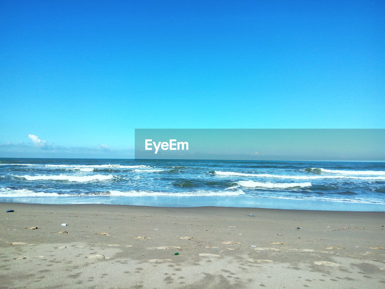 Scenic view of beach against clear blue sky