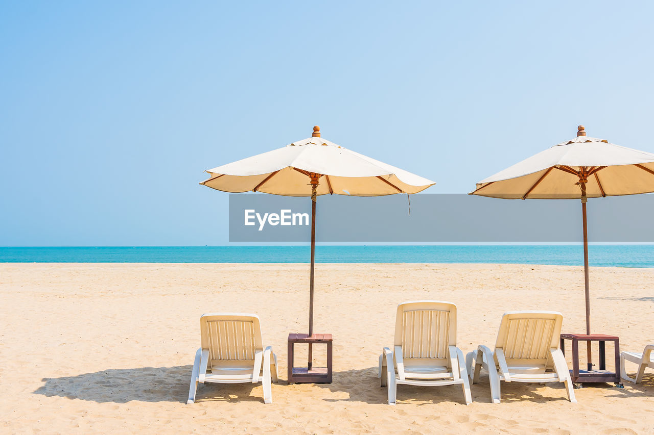 DECK CHAIRS ON BEACH AGAINST SKY