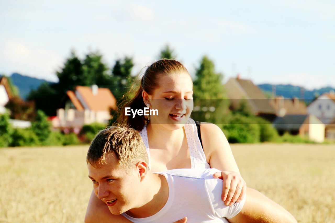 Cheerful couple enjoying on field against sky