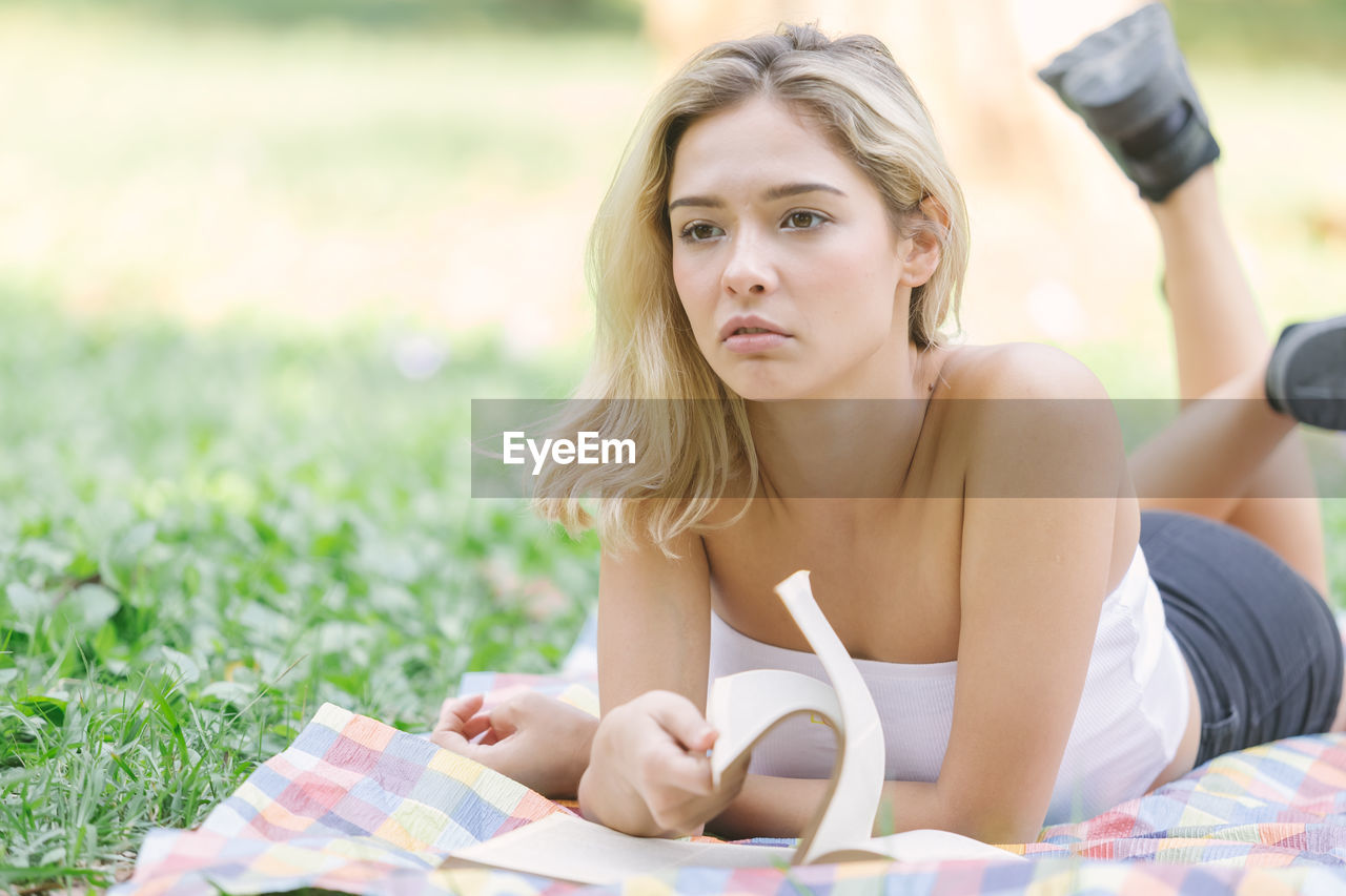 Young woman lying down on grass at park