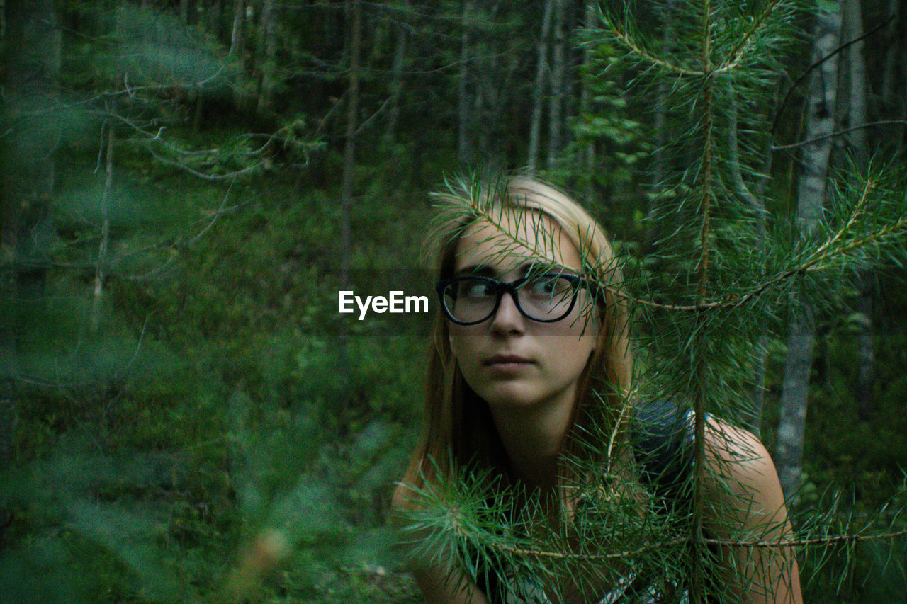 Young woman looking away while standing in forest