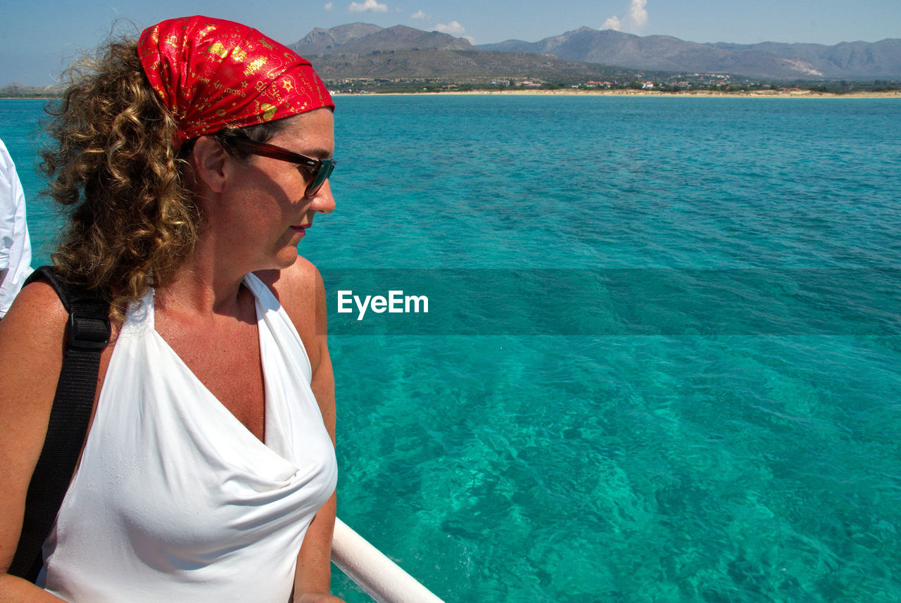 Midsection of woman wearing sunglasses at sea shore