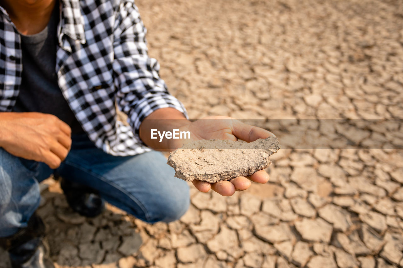 Low section of man holding dried mud