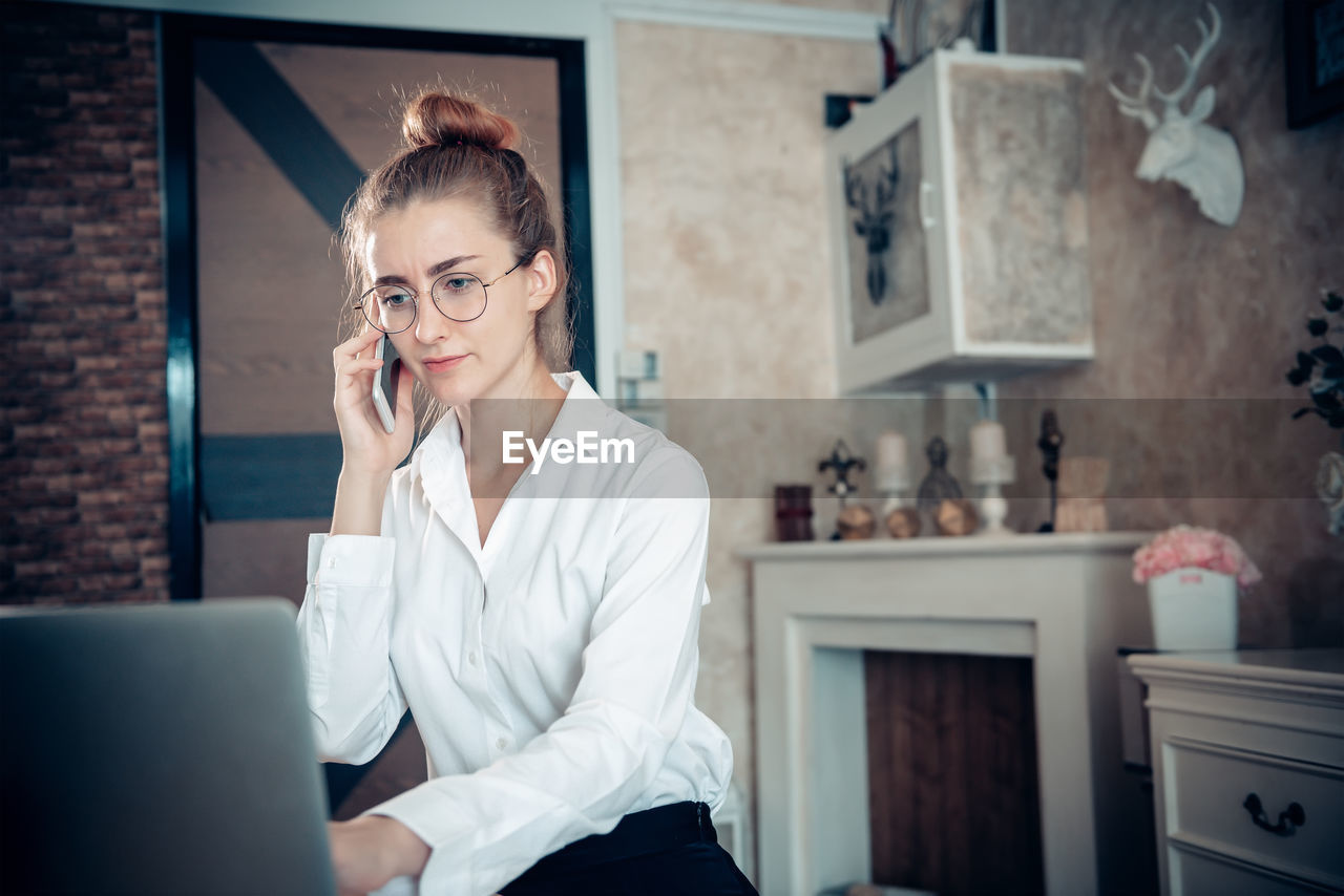 YOUNG WOMAN USING PHONE AT HOME