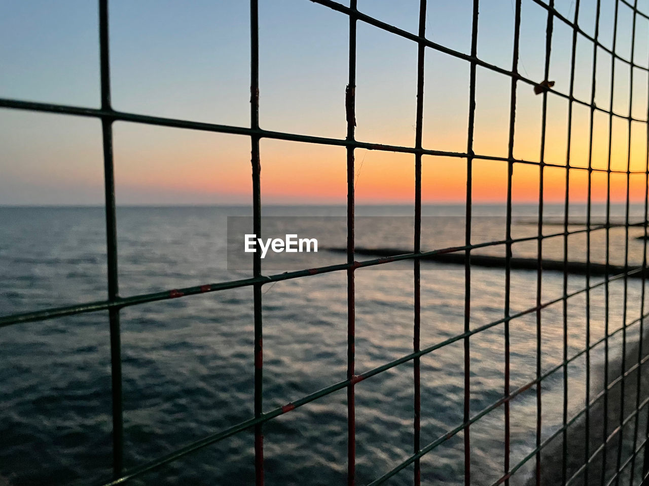 SCENIC VIEW OF SEA SEEN THROUGH FENCE